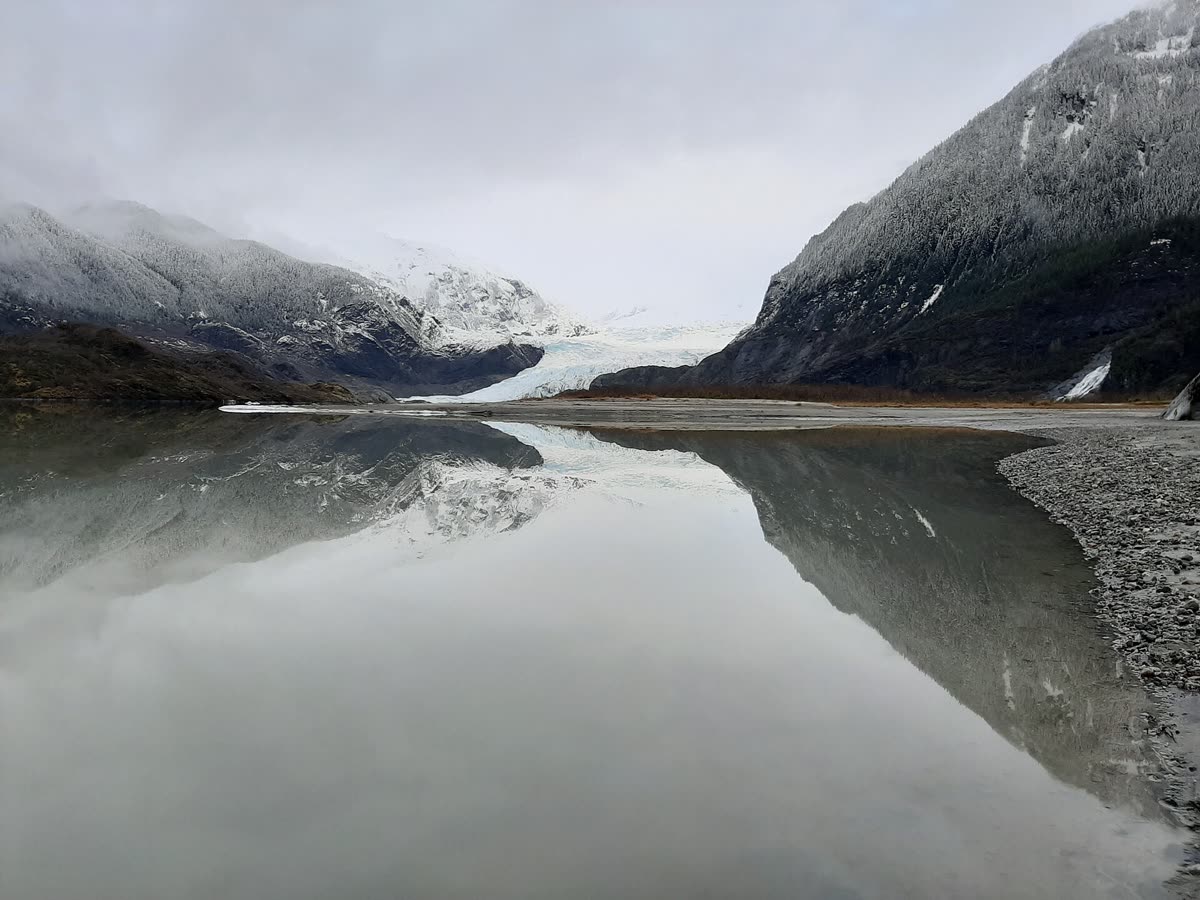 Mendenhall Glacier near Juneau, Alaska, blue ice meeting a still lake below forested ridges