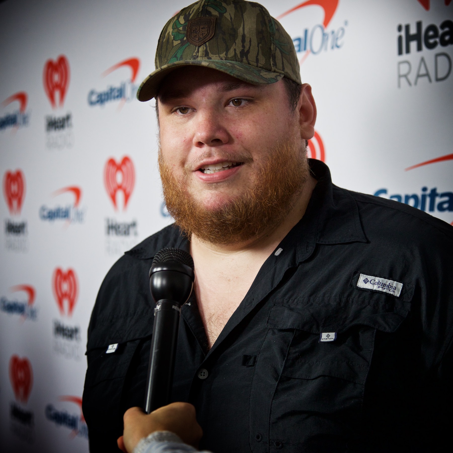 Luke Combs smiling in a cap