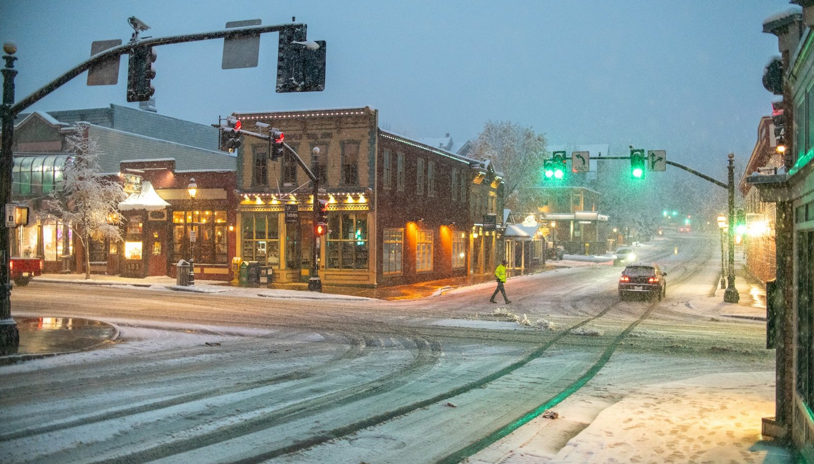 Snow falling on a quiet Colorado mountain-town main street at dusk.