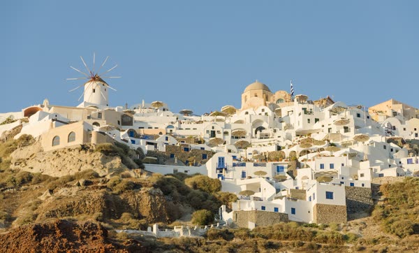 Whitewashed houses and blue domes of Oia on Santorini stepping down the cliff above the Aegean Sea