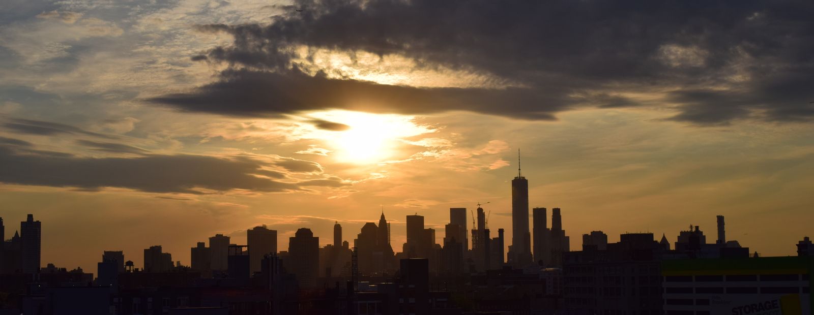 The Manhattan skyline in silhouette against a cloudy sunset