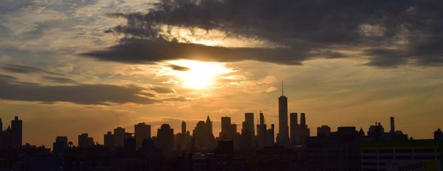 The Manhattan skyline in silhouette against a cloudy sunset