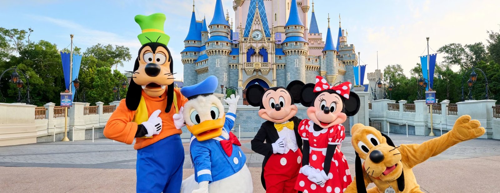 Costumed Disney characters waving in front of Cinderella Castle on a bright day