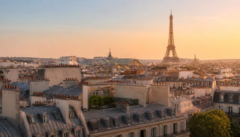 Paris rooftops at golden hour with the Eiffel Tower on the horizon